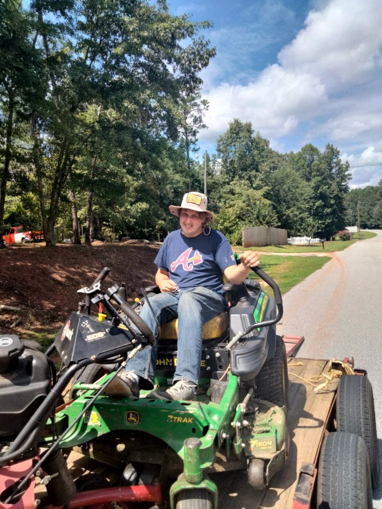 Jesse Edwards of Edwards Landscaping on a John Deere zero-turn mower ready for a lawn care job in Covington, GA